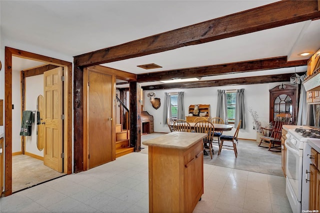 kitchen with beam ceiling, white range oven, and light colored carpet