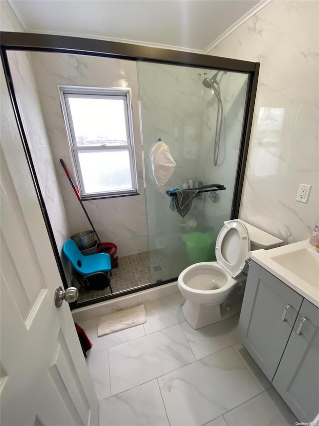 bathroom with vanity, a shower with shower door, tile walls, and toilet