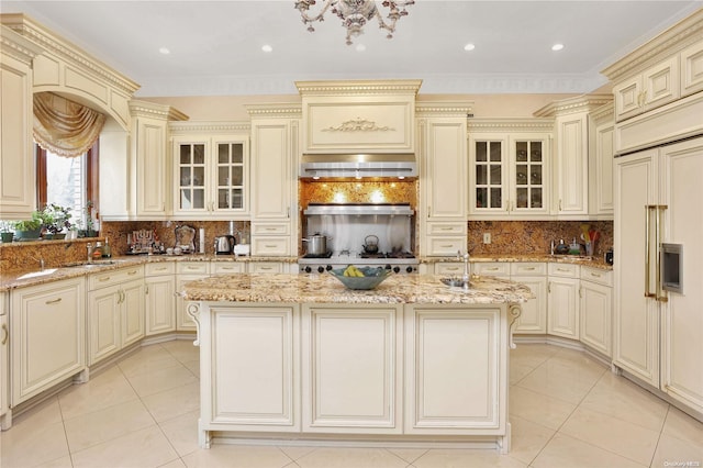 kitchen featuring a center island with sink, ornamental molding, and cream cabinets