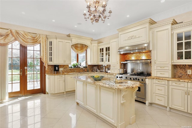 kitchen with cream cabinetry, range hood, stainless steel range, and french doors