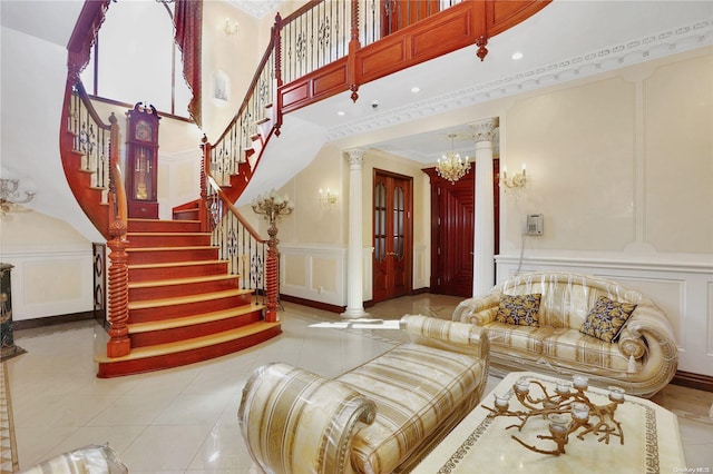 tiled living room with a chandelier, crown molding, a high ceiling, and decorative columns