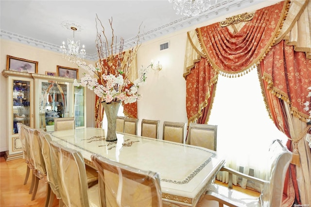 dining space featuring light hardwood / wood-style flooring, crown molding, and a notable chandelier