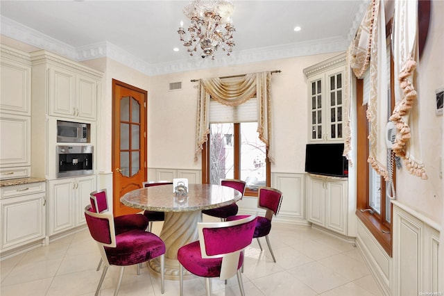 dining space with a chandelier, light tile patterned floors, and ornamental molding