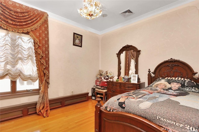 bedroom with wood-type flooring, an inviting chandelier, and crown molding