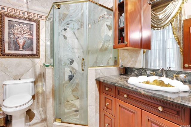 bathroom featuring vanity, toilet, a shower with shower door, and tile walls