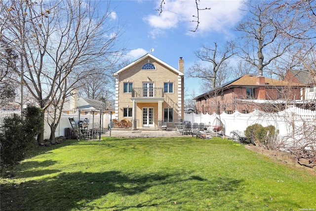 back of house with a yard, a patio area, and a balcony