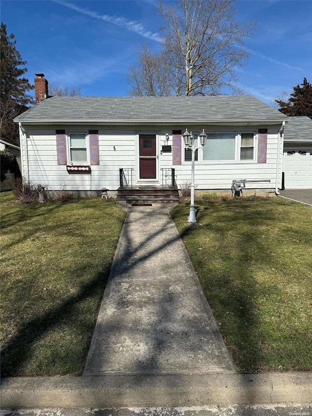 single story home with an outbuilding, a garage, and a front lawn