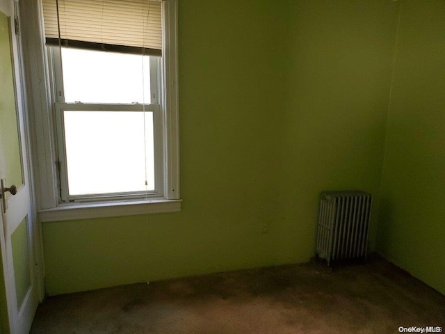 unfurnished room featuring carpet and radiator