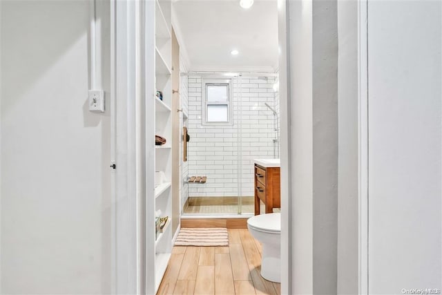 bathroom featuring walk in shower, vanity, hardwood / wood-style flooring, tile walls, and toilet