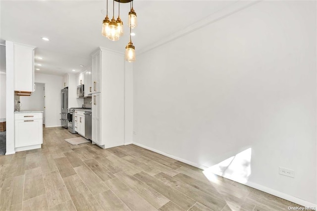 kitchen with white cabinetry, hanging light fixtures, light hardwood / wood-style floors, and appliances with stainless steel finishes