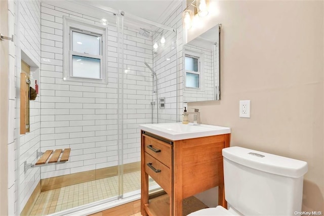 bathroom featuring ornamental molding, vanity, a shower with shower door, and toilet