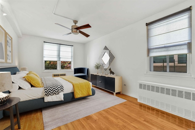 bedroom featuring hardwood / wood-style floors, radiator heating unit, and ceiling fan