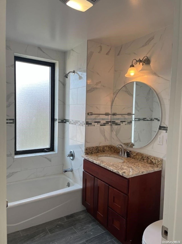 bathroom with vanity, tile walls, and tiled shower / bath