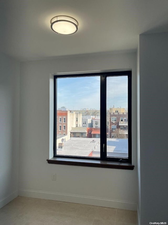 empty room featuring light tile patterned floors and a healthy amount of sunlight