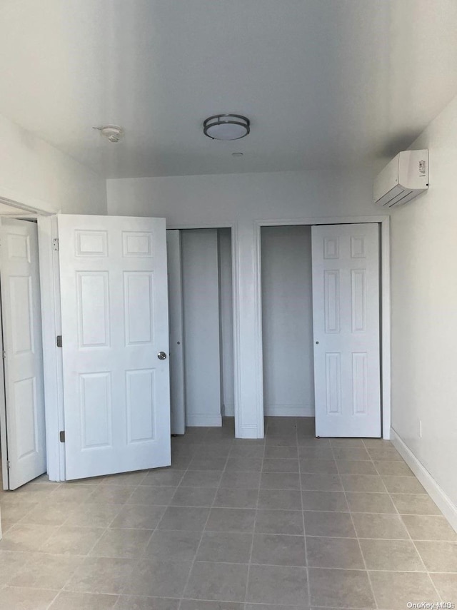 unfurnished bedroom featuring a wall mounted AC and tile patterned flooring