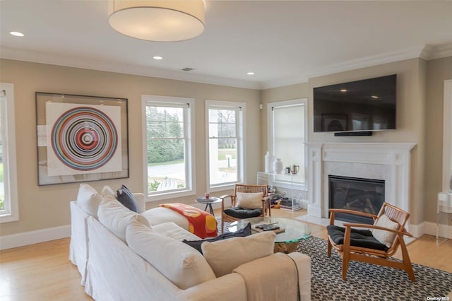 living room featuring crown molding, a high end fireplace, and light hardwood / wood-style floors