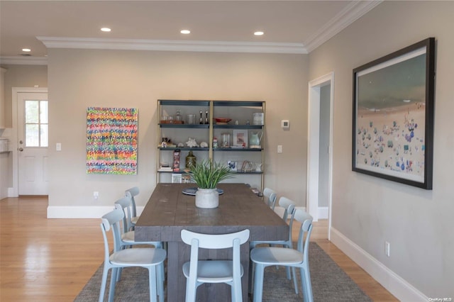 dining space featuring light hardwood / wood-style floors and crown molding