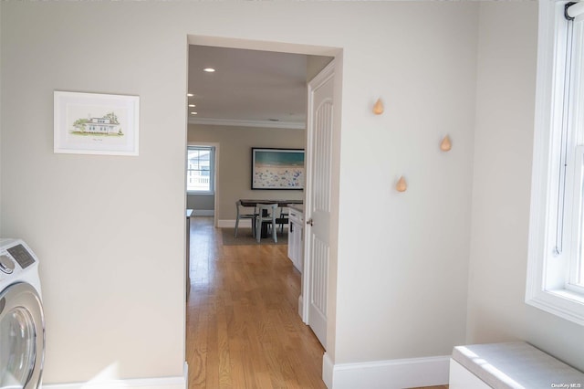 hallway featuring ornamental molding, washer / dryer, and light wood-type flooring