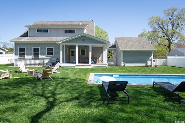 back of house with a fenced in pool, ceiling fan, and a lawn