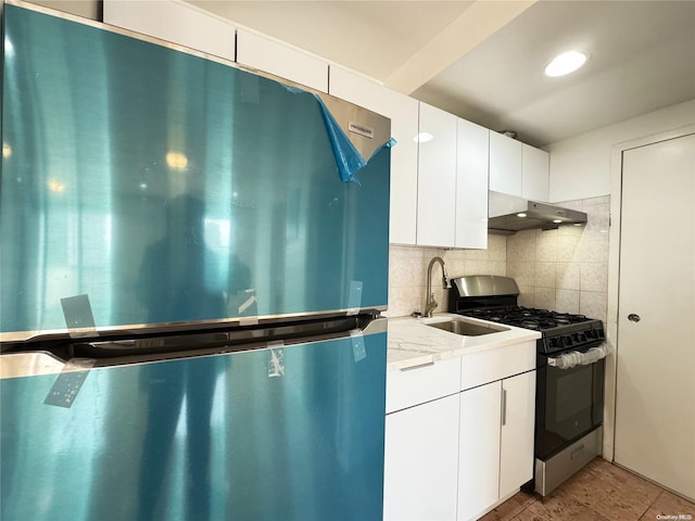 kitchen featuring white cabinetry, sink, stainless steel appliances, light stone counters, and decorative backsplash