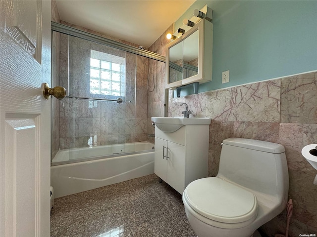 full bathroom with vanity, toilet, shower / bath combination with glass door, and tile walls