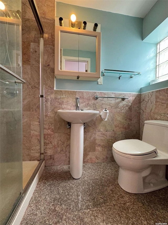 bathroom featuring a shower with door, tile walls, and toilet