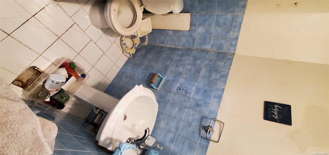 bathroom featuring tile patterned floors, toilet, and tile walls