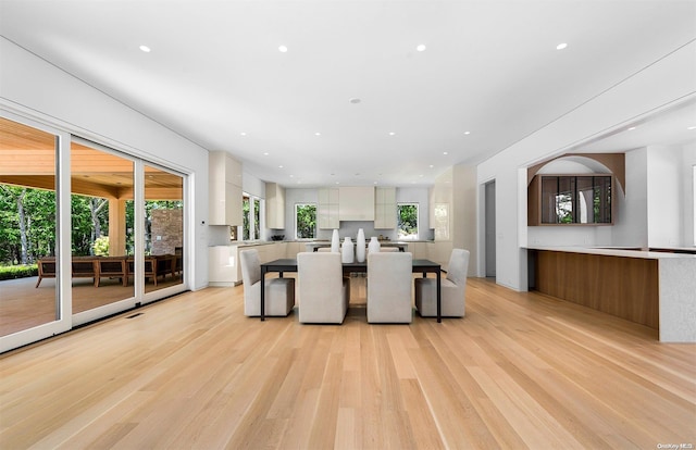 kitchen featuring white cabinets, a kitchen bar, light wood-type flooring, and a kitchen island with sink