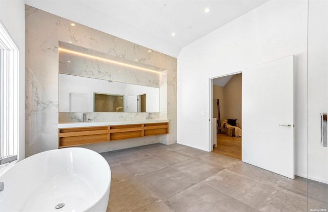 bathroom with a bathing tub, vanity, and tile walls