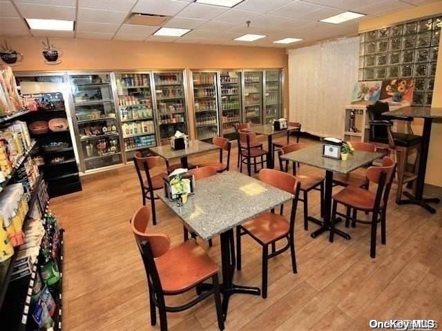 dining room with a drop ceiling and light hardwood / wood-style flooring