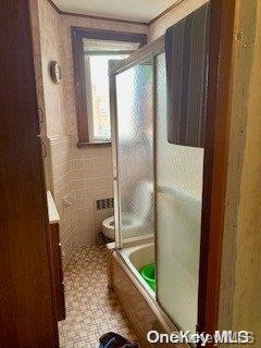 full bathroom featuring combined bath / shower with glass door, vanity, and toilet