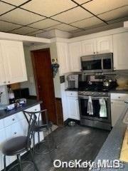 kitchen featuring a paneled ceiling, white cabinets, and appliances with stainless steel finishes