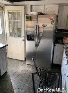 kitchen with white cabinets, wood-type flooring, and stainless steel refrigerator with ice dispenser