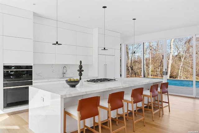 1739 Millstone Rd, Sag Harbor, NY 11963 - kitchen with stainless steel gas stovetop, modern cabinets, a sink, black oven, and light wood-type flooring