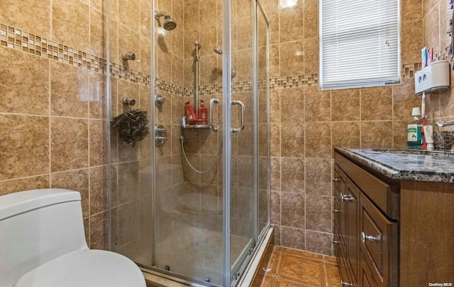 bathroom with tile patterned floors, a shower with door, vanity, and tile walls