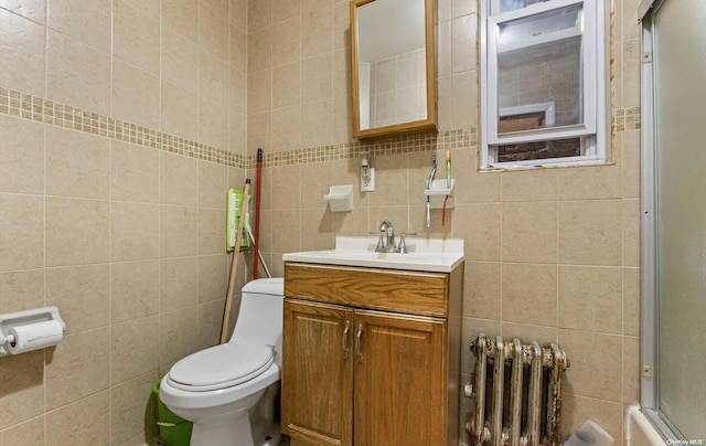 bathroom with backsplash, vanity, tile walls, radiator heating unit, and toilet