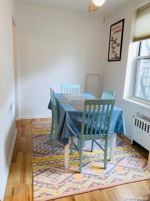 dining space with hardwood / wood-style floors and radiator heating unit