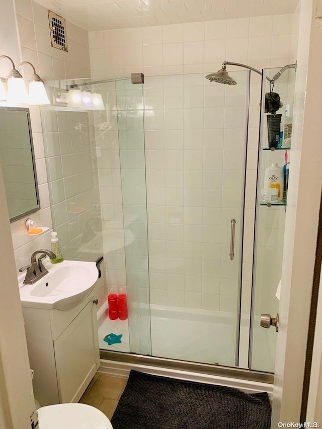 bathroom featuring tile patterned flooring, vanity, toilet, and walk in shower