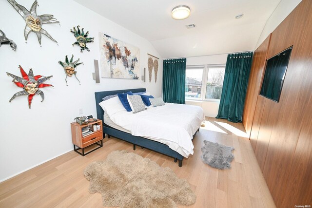 bedroom with light wood-type flooring and lofted ceiling