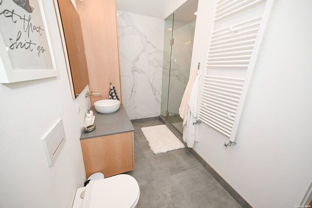 bathroom featuring radiator heating unit, vanity, toilet, and a shower with shower door