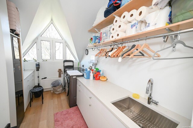 washroom featuring cabinets, radiator heating unit, light wood-type flooring, and sink