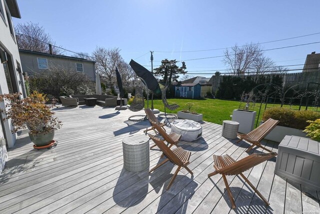 deck with a yard, a shed, and an outdoor living space with a fire pit