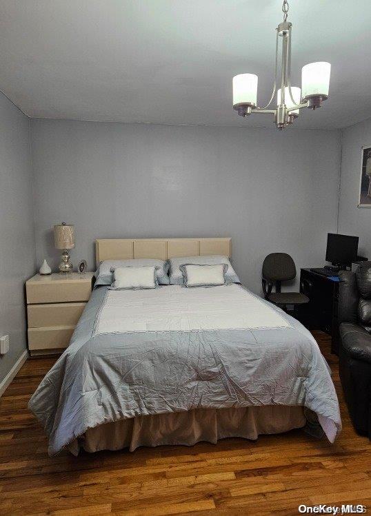 bedroom with dark hardwood / wood-style flooring and a chandelier