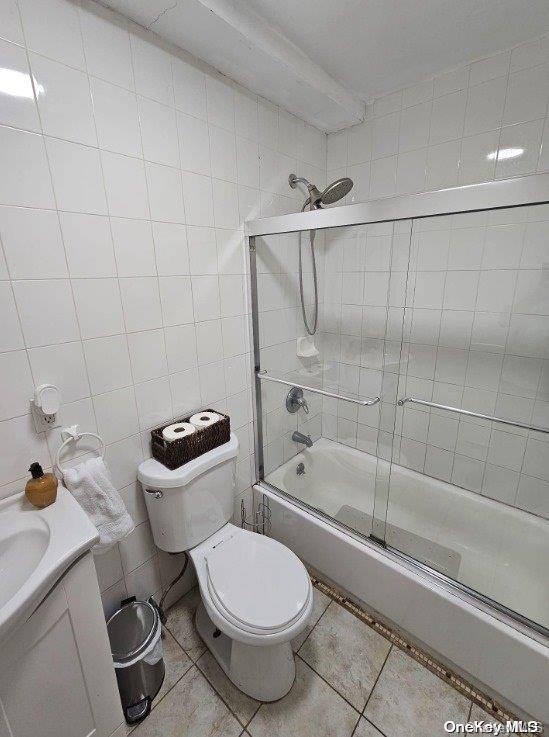 full bathroom with shower / bath combination with glass door, vanity, tile patterned floors, and tile walls