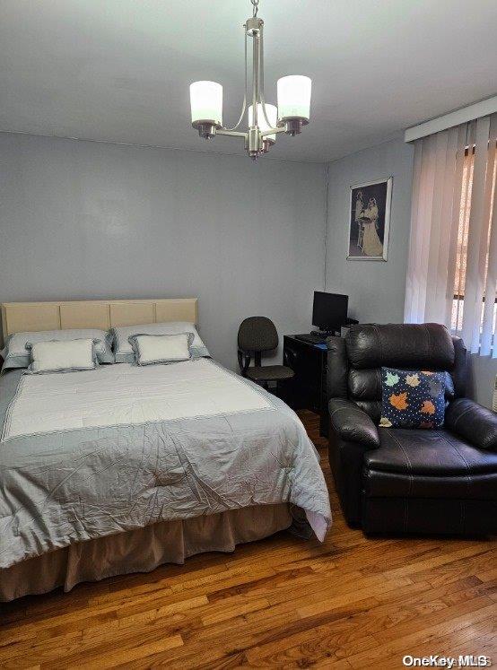 bedroom with hardwood / wood-style floors and a chandelier