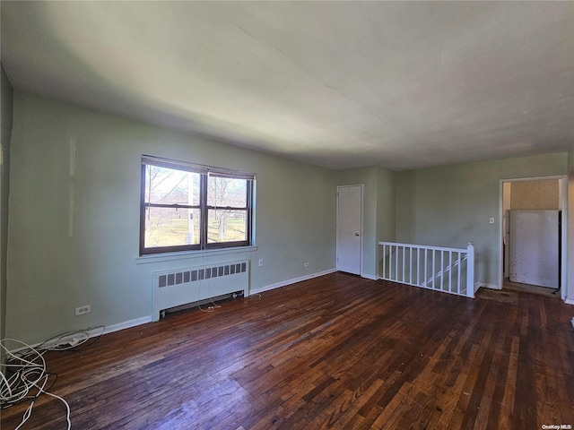 spare room featuring radiator heating unit and dark hardwood / wood-style floors