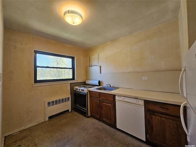 kitchen with dark brown cabinetry, white appliances, radiator, and sink