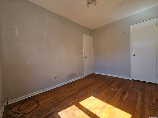 spare room featuring vaulted ceiling and hardwood / wood-style flooring