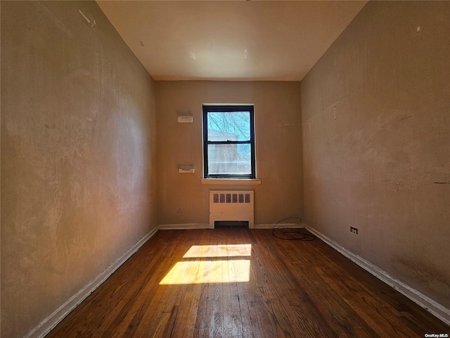 empty room with wood-type flooring and radiator