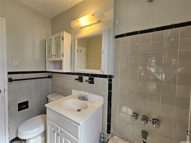 bathroom featuring vanity, tile walls, and toilet